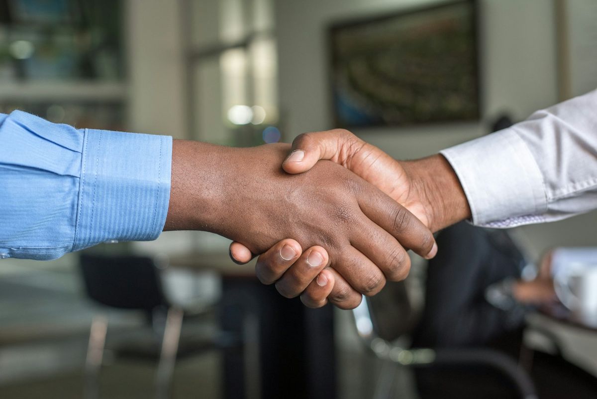 Two people shaking hands across a table after reaching an agreement.