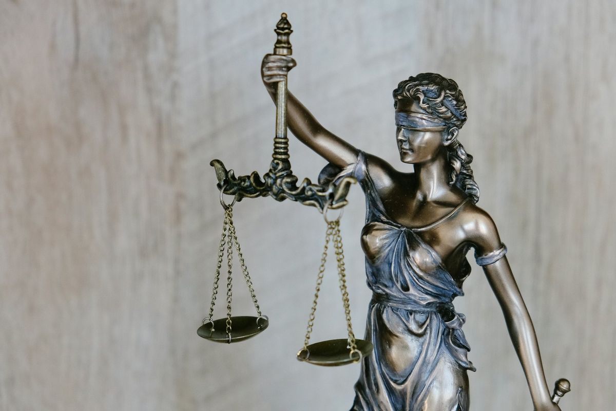 A bronze statue of Lady Justice holding balanced scales.